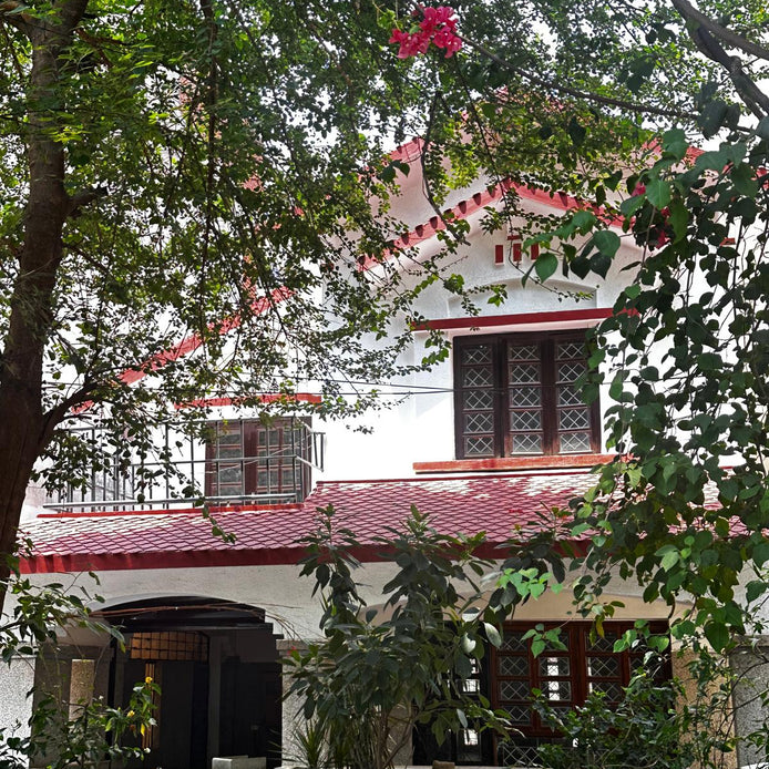 Traditional house with red roof and white walls, surrounded by greenery